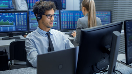 Stock Trader Making Sales with a Headset. In the Background Stock Exchange Office and Group of...