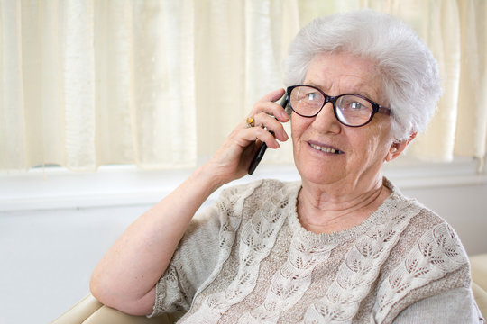 Old woman talking on the telephone at home.