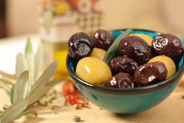 Close up view of green and black olives in porcelain bowl with olive oil  with a shallow depth of focus
