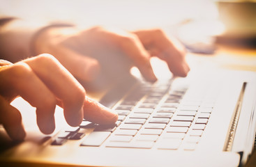 A closeup of an office worker using a computer keyboard, laptop on a sunny morning, evening.