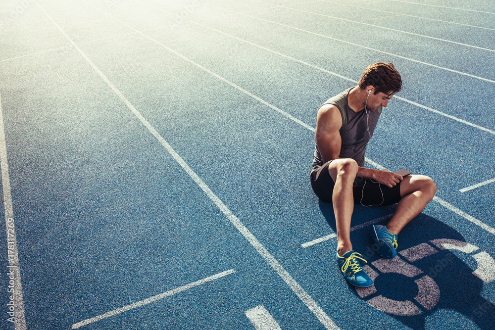 Wall mural sprinter relaxing on running track