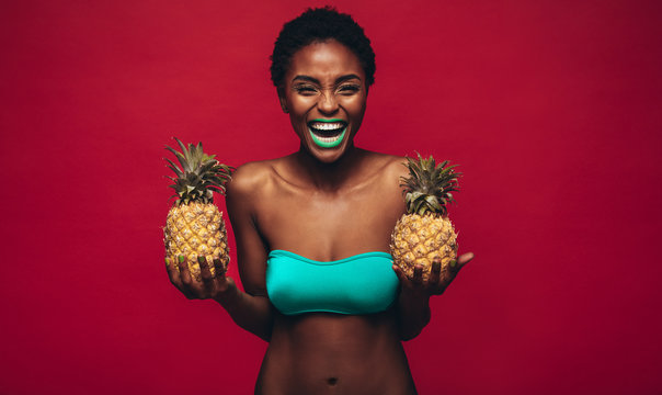 Happy african woman holding fresh pineapples