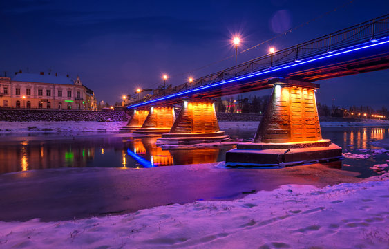 bridge through the river Uzh at night. beautiful cityscape of old european town Uzhgorod in winter