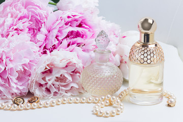 Female lifestyle scene with fresh pink peony flowers, glamour bottles and jewellery close up
