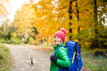 Hiking woman with backpack looking at inspirational autumn golden woods