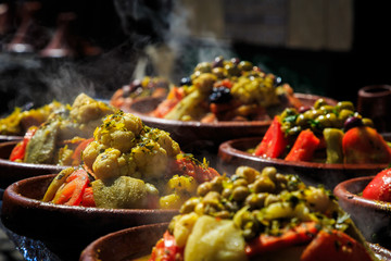 A lot of warm tagines with delicious vegetables on a market