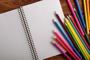  blank paper and colorful pencils on old wooden table