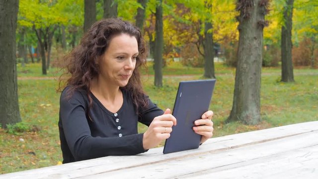 Woman with a tablet in an autumn park.