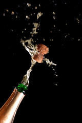 Cork flies out of champagne bottle isolated on black background © Ivan