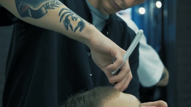 Barbershop. A hairdresser is creating a fashionable image for the young guy.