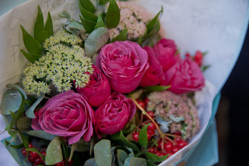 Closeup shot of red bouquet of roses, gerberas, peonies, pomegranates. Love and passion symbol. Anniversary or birthday gift for girl.