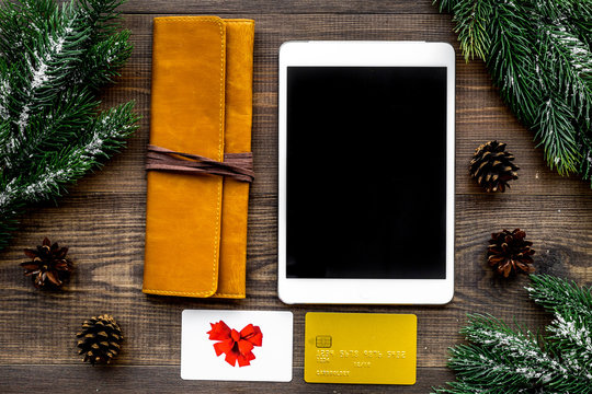 Buy new year gift online on sale. Tablet, wallet and gift card on wooden background top view