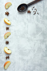 Recipe background with apple wedges, star anise, wooden spoon and cloves