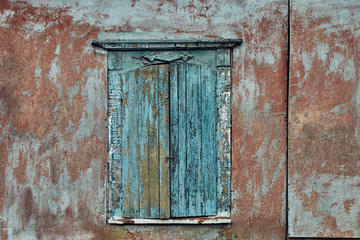Old wooden shutters on the wall with cracked paint.