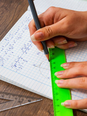 schoolgirl solves the problem of mathematics. school, education, people and learning concept - close up of student or woman hands with ruler and pencil drawing line in notebook