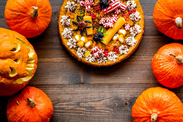 Homemade pie for halloween decorated gummy spiders among pumpkins on wooden background top view copyspace