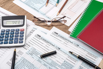 tax form with notepad, pen, pencil and calculator