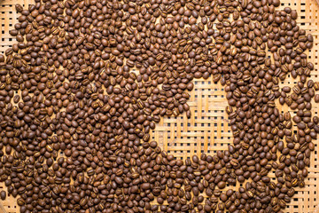 Flay lay style, Medium dark Roasted peaberry coffee beans with heart shape on bamboo handcraft background. coffee lover concept.