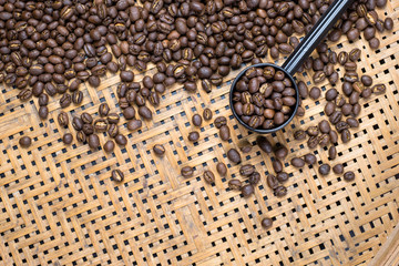 Flay lay style, Medium dark Roasted peaberry coffee beans in plastic cup spoon on bamboo handcraft background with copy space for text.