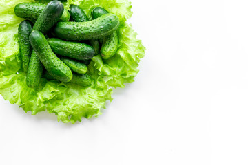 Heap of fresh cucumbers on salad's leaves on white background top view copyspace