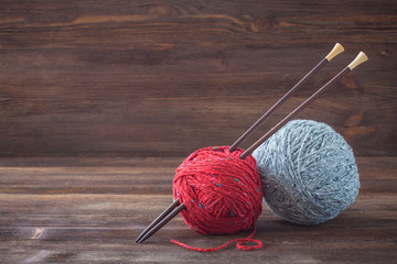 Tweed wool yarn with wooden knitting needles. Wooden background