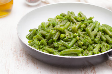 green beans on frying pan on wooden background
