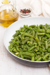 green beans on frying pan on wooden background