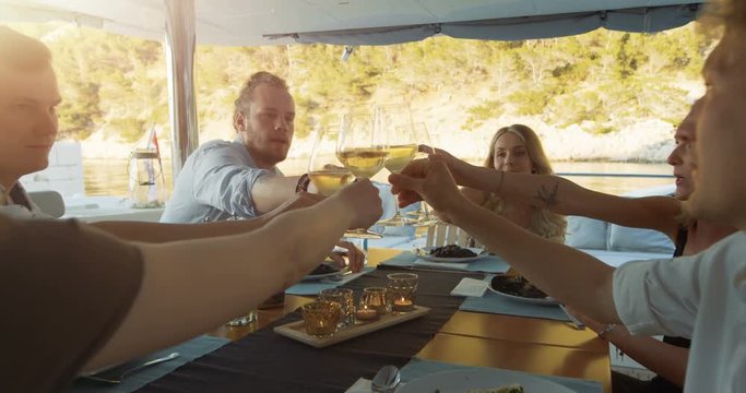 Company of Young People on a Yacht, They Clink Glasses in Celebration. Table Served with Steamed Mussels. Beautiful Seaside View. Shot on RED Epic 4K UHD Camera.