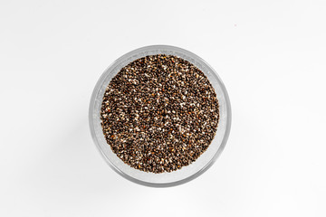 Dark chia seeds in glass bowl on white background top view copyspace