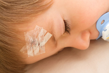 a child with a band-aid on stitched forehead in an accident