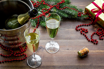 Champagne for celebrate new year. Glasses, bottle in bucket, spruce branch, decoration on wooden background