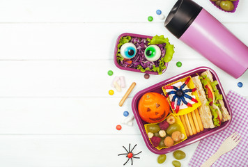 Halloween lunch box with school lunch and thermo mug on white wooden background