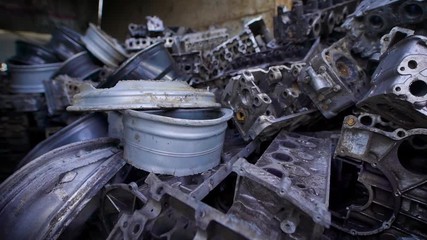 metal parts of old broken automobiles are lying in heaps of scrap metal in large hangar, old humps and engines - Powered by Adobe