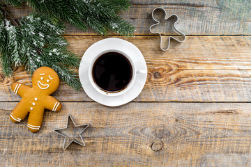 Obraz na płótnie Canvas Christmas evening. Gingerbread man, coffee and spruce branch on wooden background top view copyspace