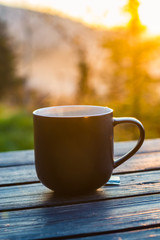 Still life with cup of coffee on the carpathian mountains background during the sunset