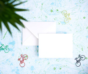 Blank greeting card on blue background surrounded by bicycle shapes