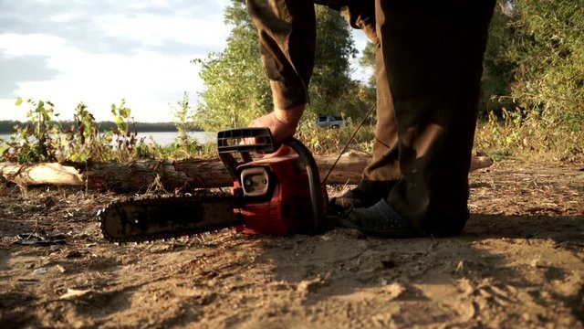 Lumberman starting chainsaw for sawing firewood