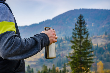 Man holding a bottle on the carpathian mountains background