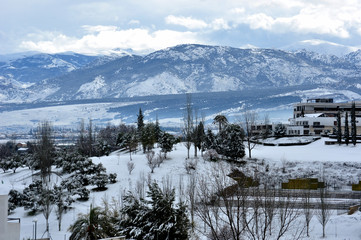 Snowy landscape with city, mountains and clouds