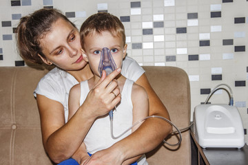 Inhaler for cough. Mom makes his son inhalation for bronchitis from coughing. Breathe in inhaler...