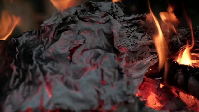 The ashes of the burnt paper in the fire flutters in the wind in the forest.