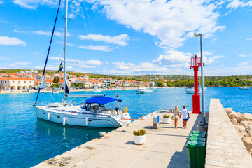 Fototapeta na wymiar Couple of unidentified tourists walking in beautiful Primosten sailing port, Dalmatia, Croatia