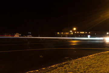 Fototapeta na wymiar Long exposure light trail of night traffic on a quiet small town main street during a mist rain