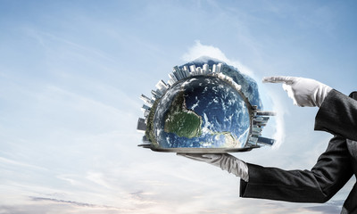 Hand of waitress presenting Earth globe on tray.