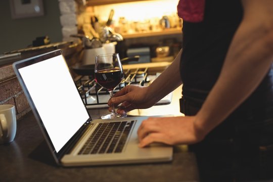 Mid section of man using laptop on kitchen worktop