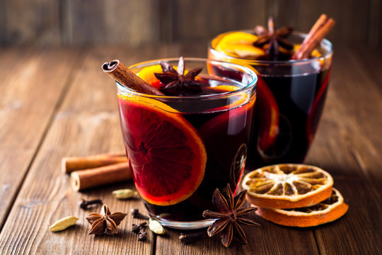 Fototapeta Two glasses of christmas mulled wine with oranges and spices on wooden background.