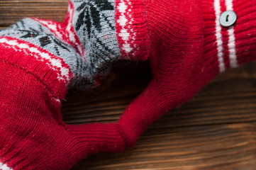 Heart shape made of hands in red knitted mittens, close-up. Concept of Valentines Day