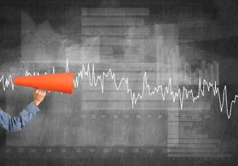 Hand of man holding red paper trumpet against graphs background