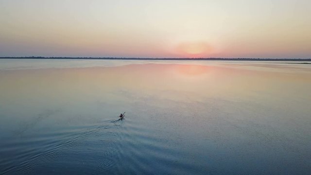 aerial footage of man kayaking on lake during sunset