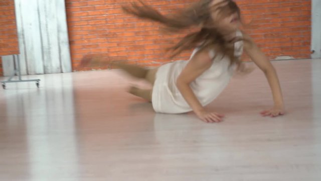 sad girl is preparing to perform in the theater. the actor rehearses the dance in the dance hall. the woman wore a white free dress. dramatic scene with a dance on the floor. professional dancer